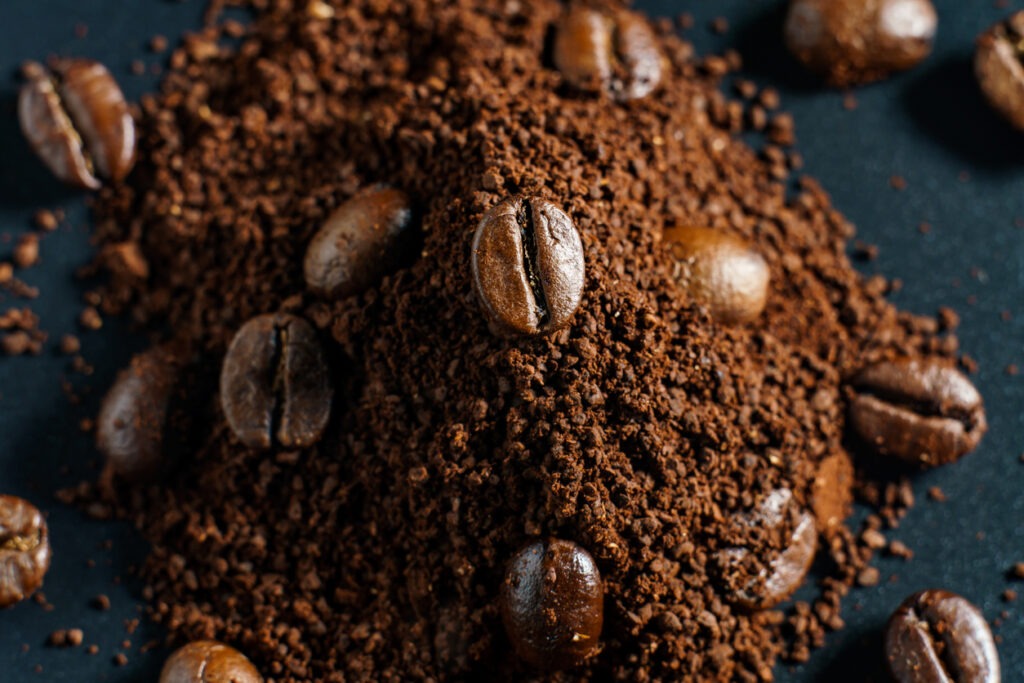 An Image of Ground coffee and coffee beans on black background