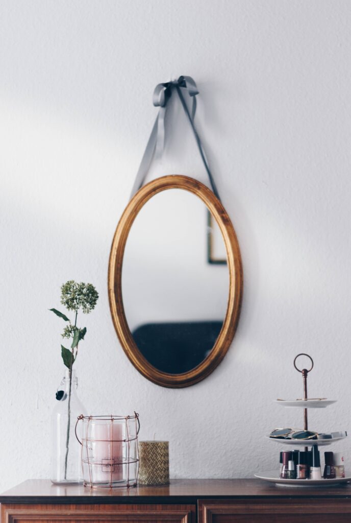 an image of a hanging oval mirror with a wooden frame