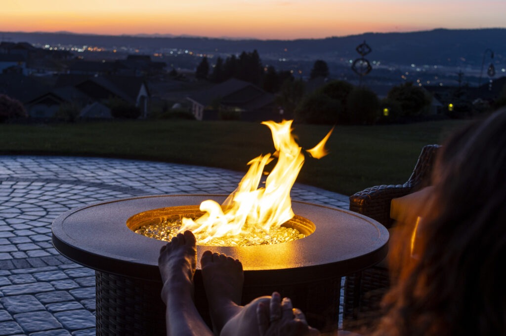 woman-relaxes-with-her-feet-on-a-back-yard-fire-pit image