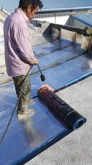 Torch-on bitumen-based waterproofing membrane being rolled out image