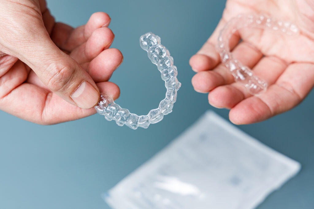 A person holding an aligner in their hands