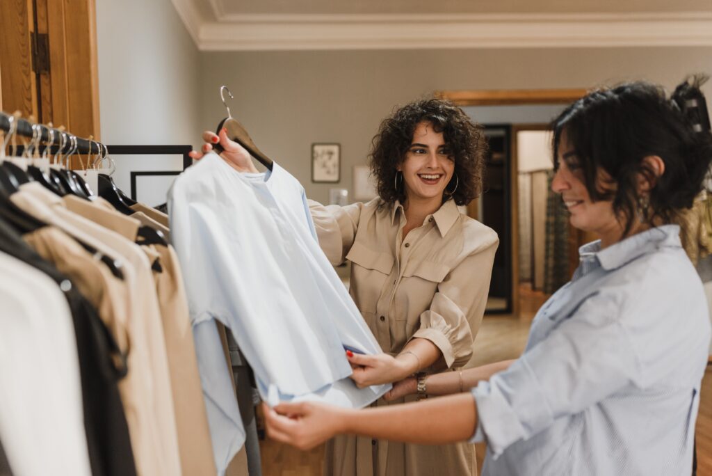 A saleswoman showing a woman a shirt