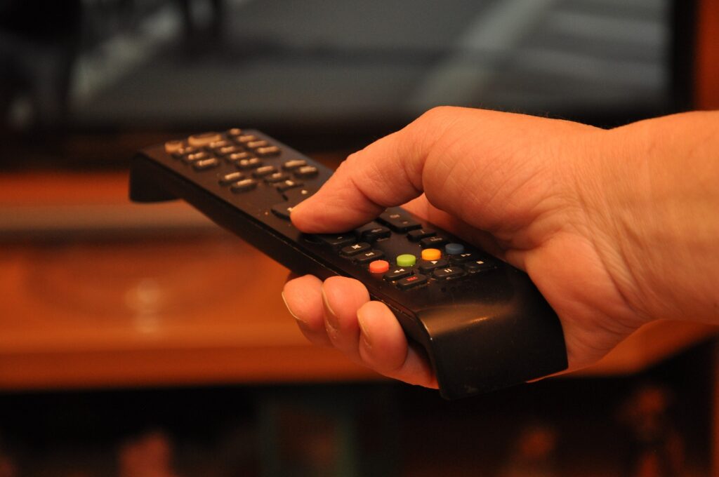  A man holding a tv remote controller.