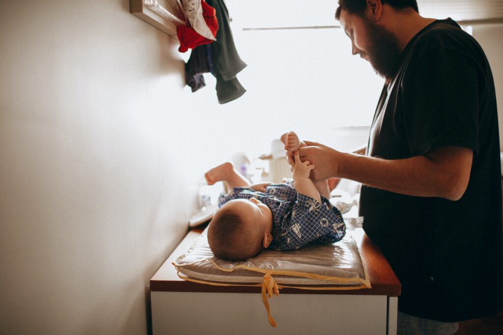 Young father changing the diaper of a newborn baby