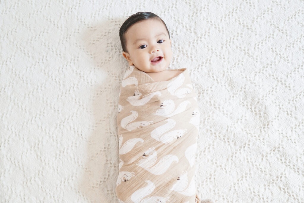 A cute Asian baby being swaddled