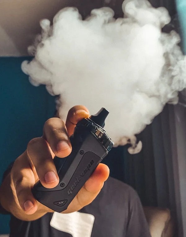 A person holding a vape with smoke coming out