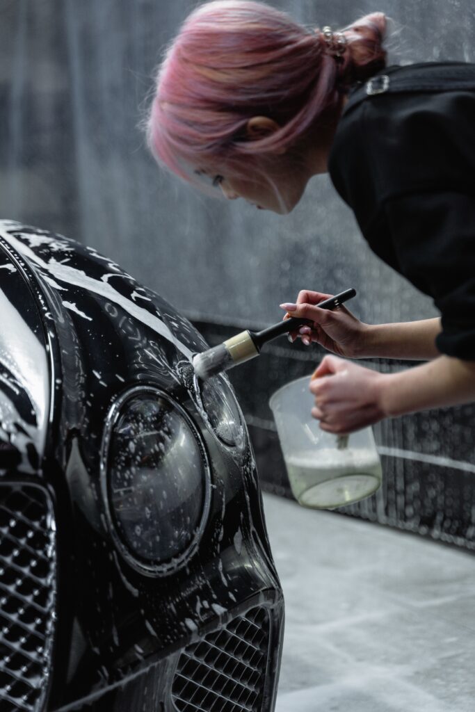 woman cleaning the headlight of a car image