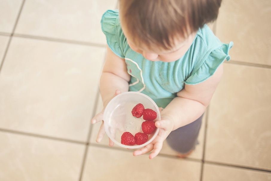 A child holding a bowl of raspberries