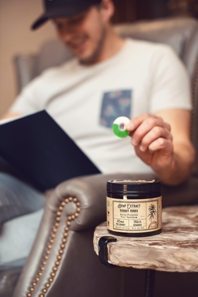 A person taking a CBD gummy from a bottle on a table image