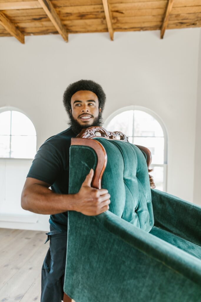 Man Smiling While Lifting a Green Armchair image