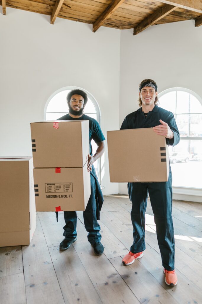 Two men standing carrying cardboard boxes image