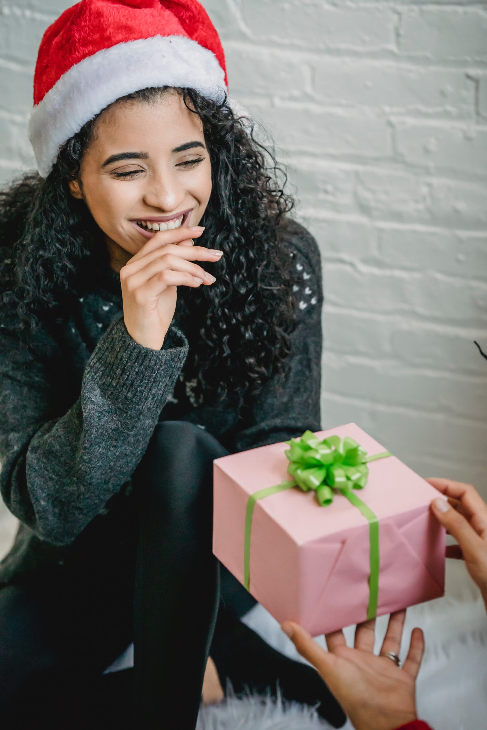 woman wearing a Santa hat getting a gift image