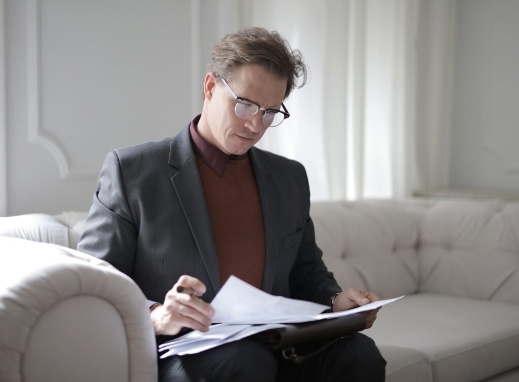 A man sitting on a couch looking over papers image
