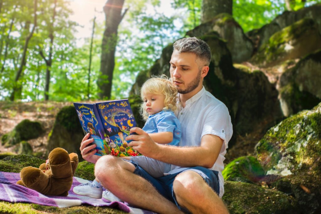 Photo of Man and Child Reading Book During Daytime