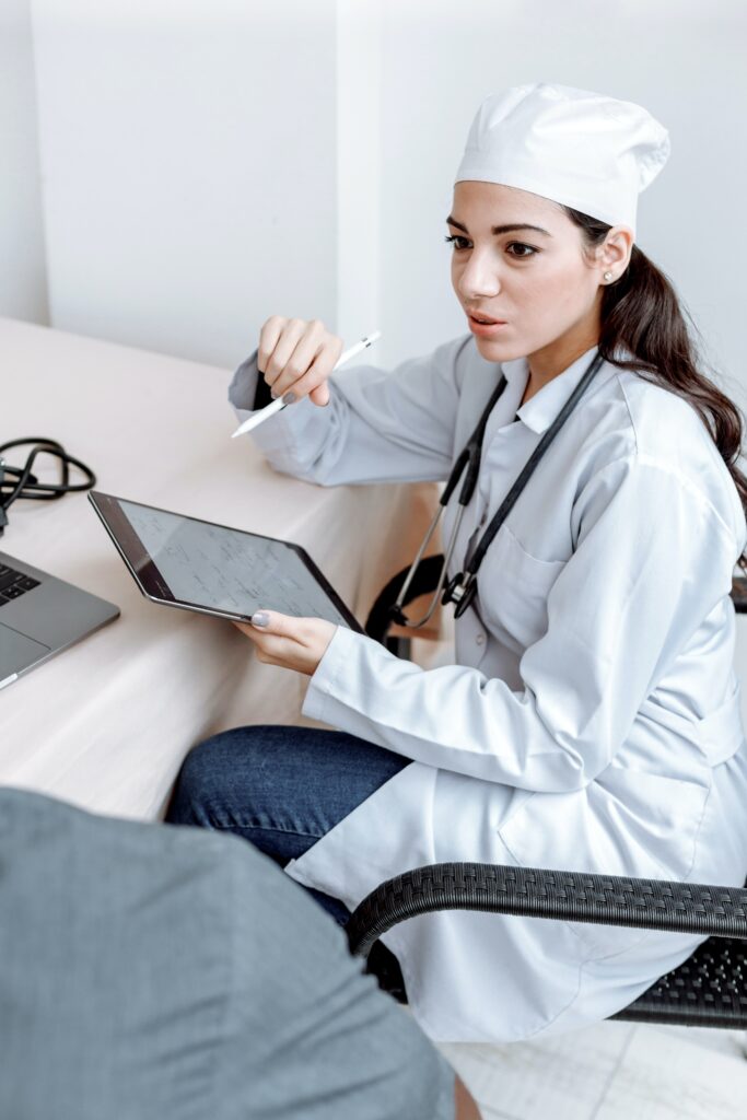 Medical Professional Sitting on a Chair Holding a Tablet while Talking
