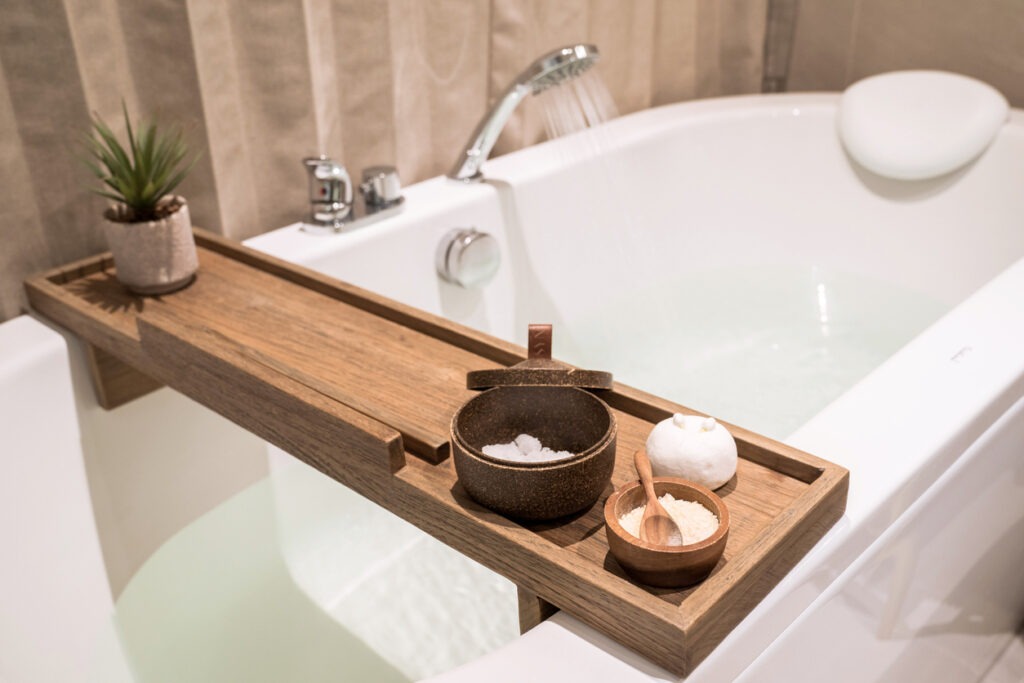 A bath tub with wooden table and toiletries