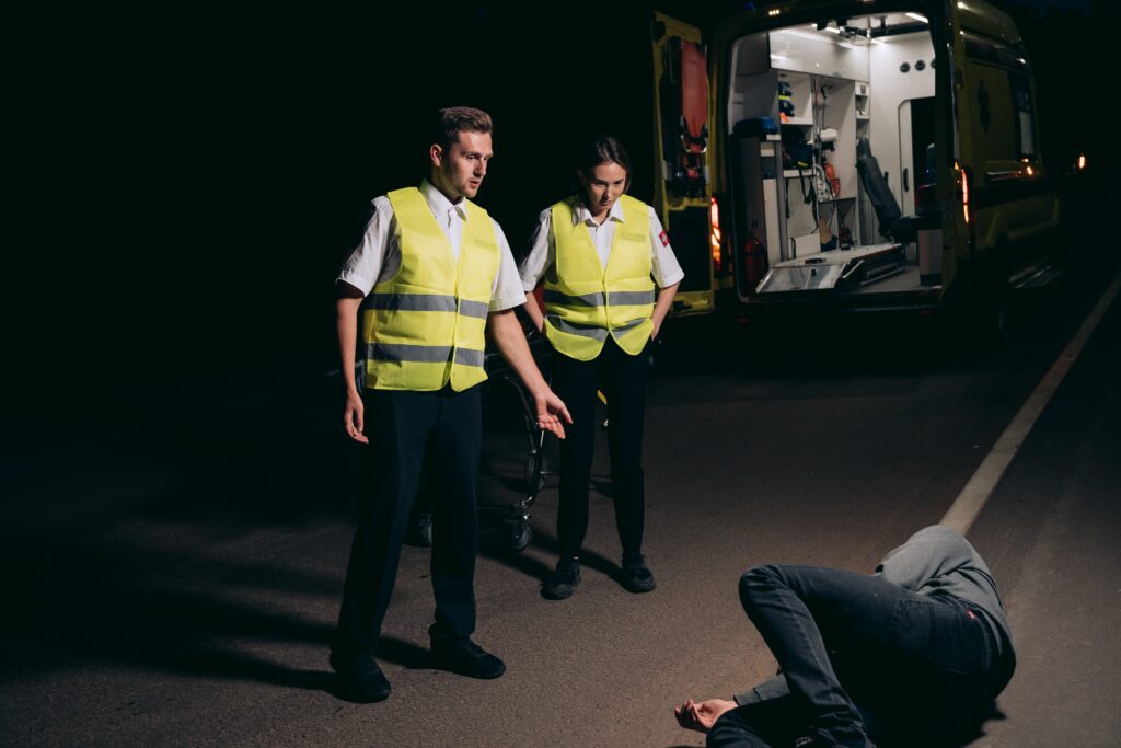 paramedics looking at the person lying on the street image