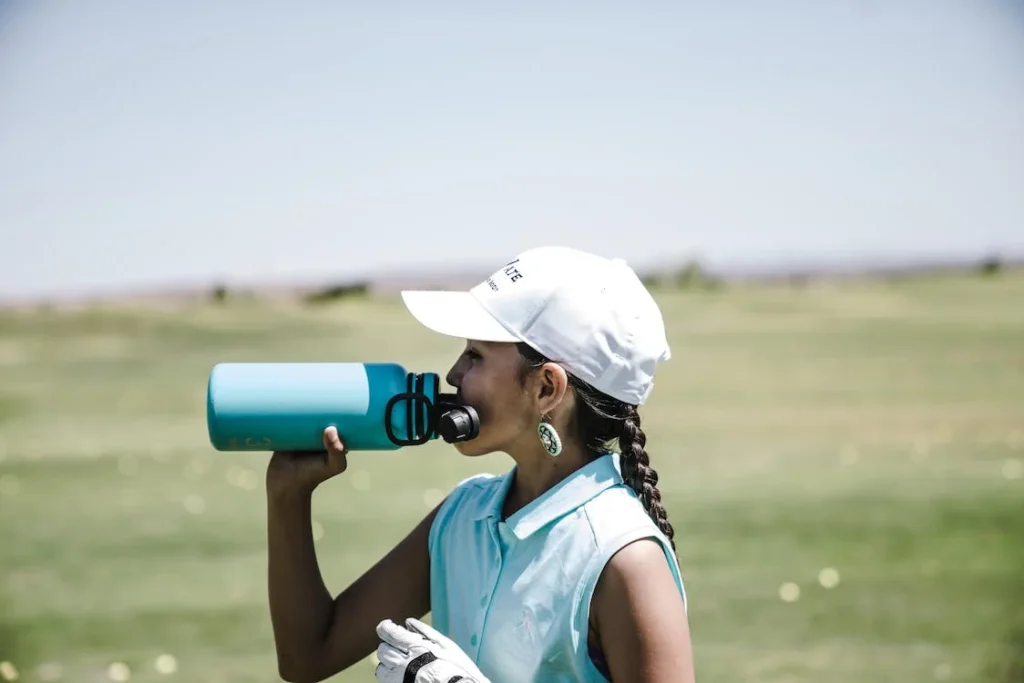 A woman drinking from a blue water bottle