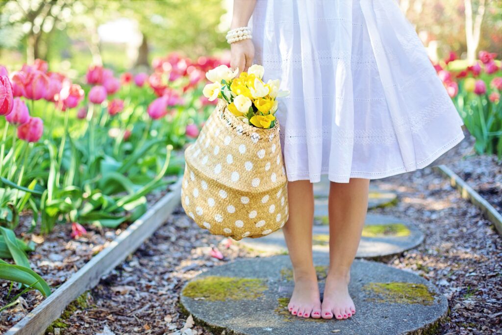 An Image of a A barefoot woman holding flowers in a basket