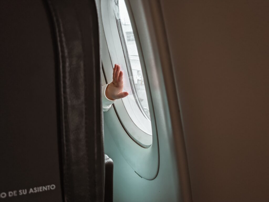 a baby’s hand touching the window in an airplane image