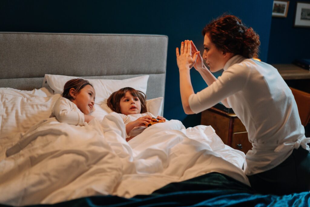 A Woman Story Telling With Two Children In Bed image