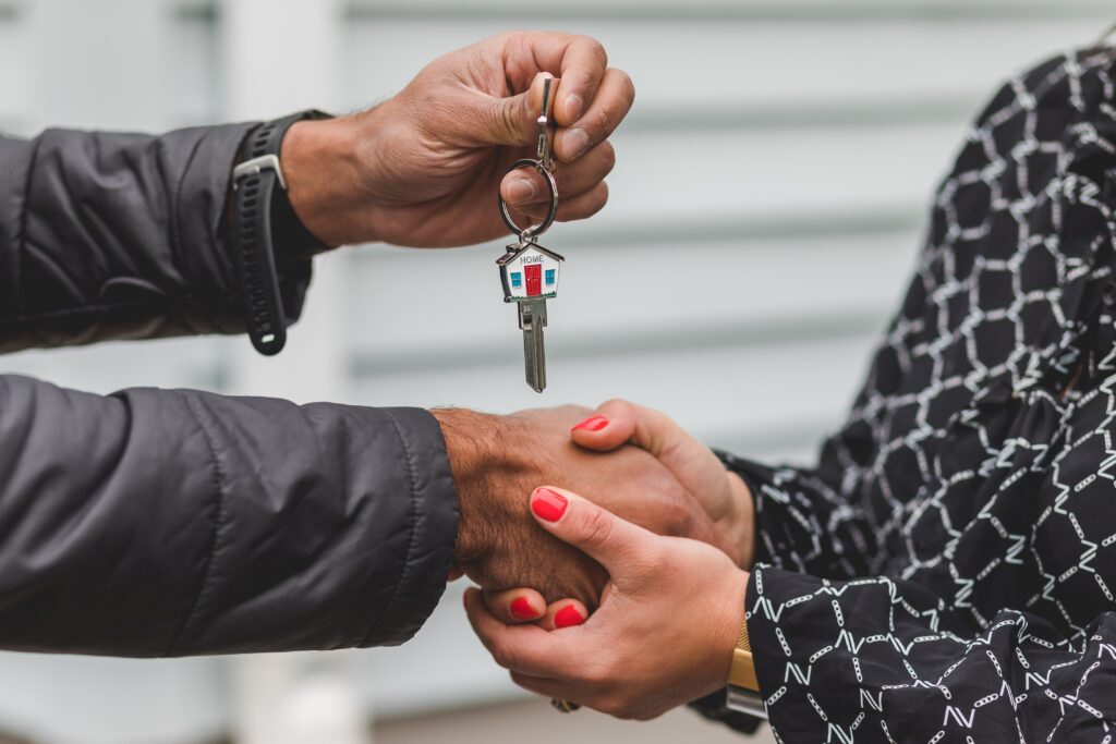 Two people shaking hands and exchanging a house key image