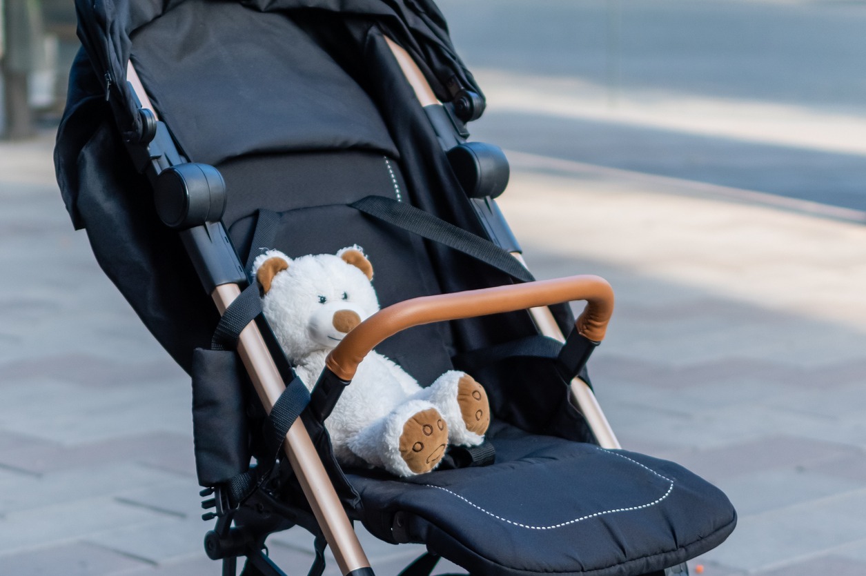 a baby stroller with a teddy bear sitting