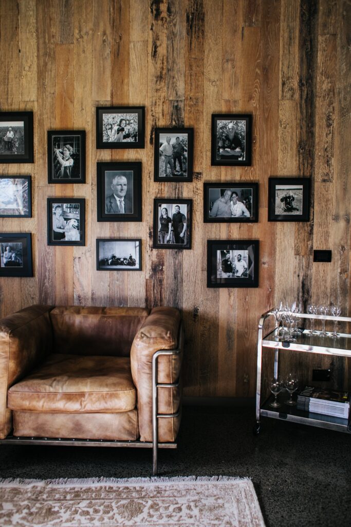 photos hanging on a wooden wall with a brown couch image