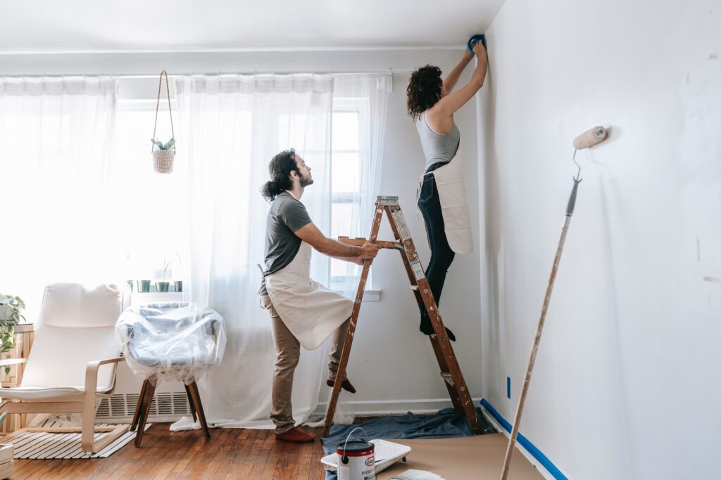 An image of a man with a woman on ladder painting