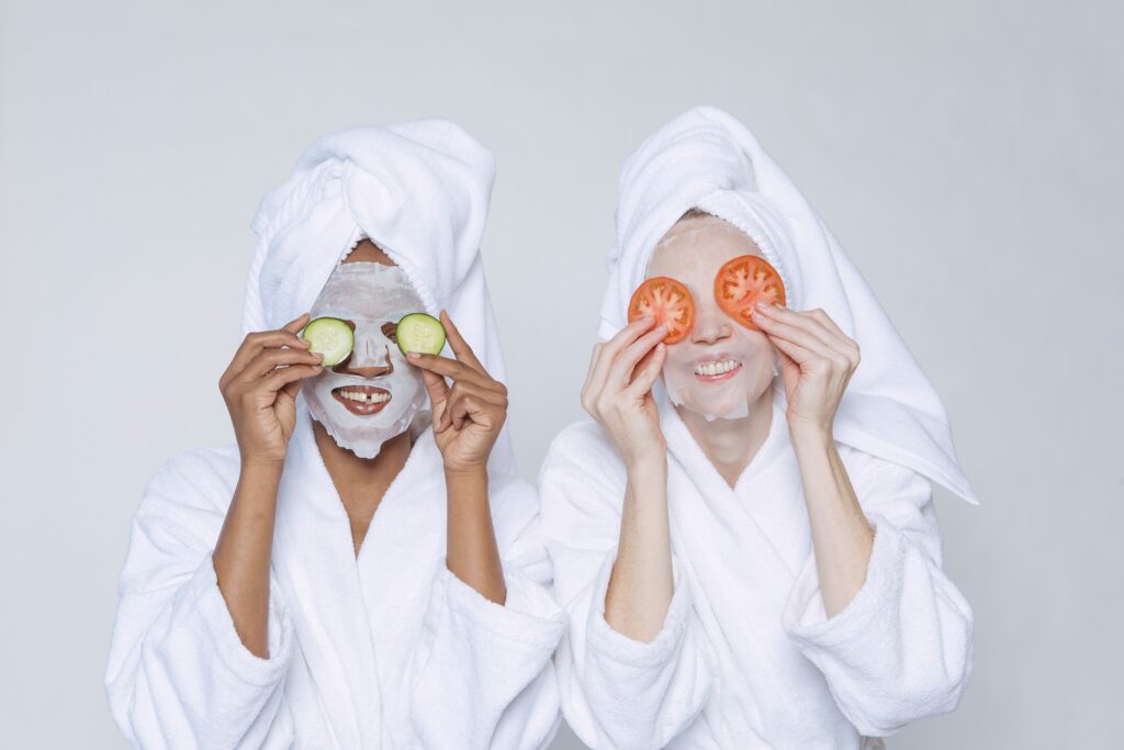 Smiling Multiethnic Women Applying Cucumber and Tomatoes On Eyes