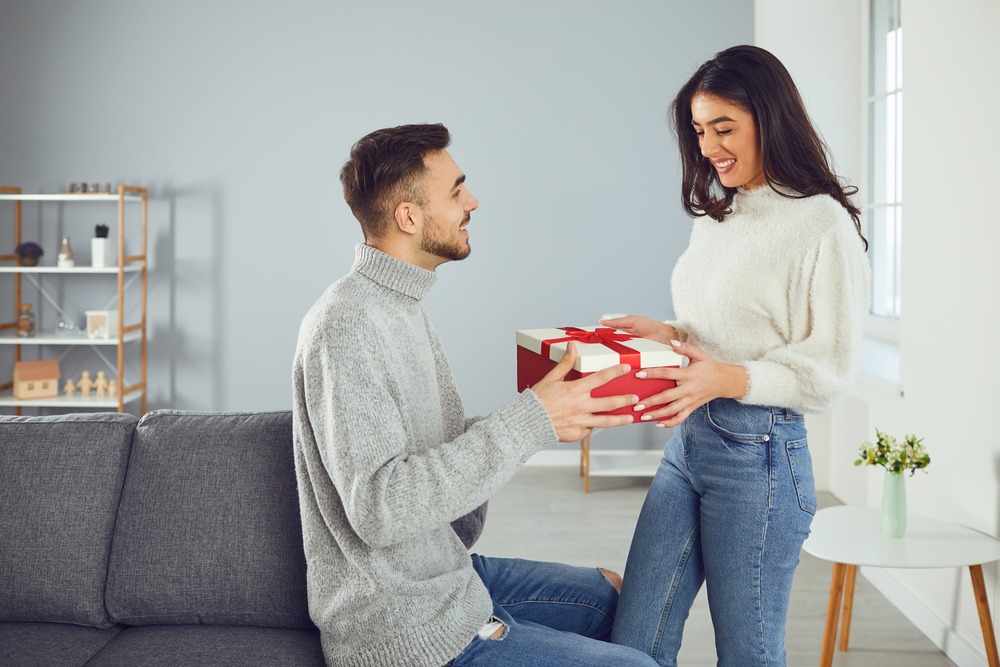 Valentine's day. A young couple gives a gift in a room