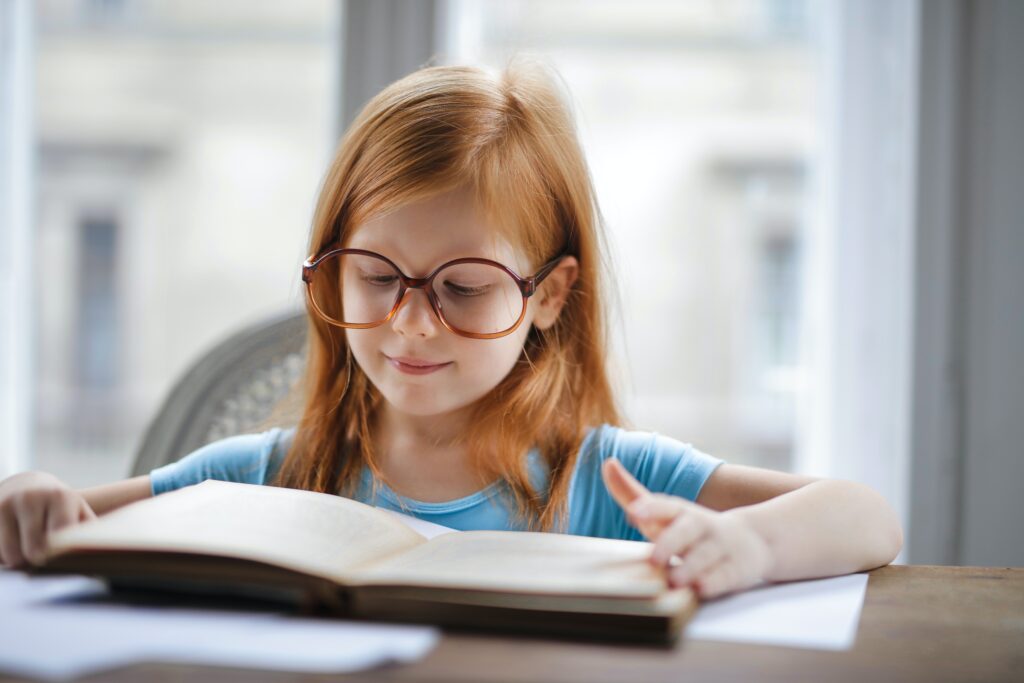 girl in blue shirt wearing eyeglasses reading book image