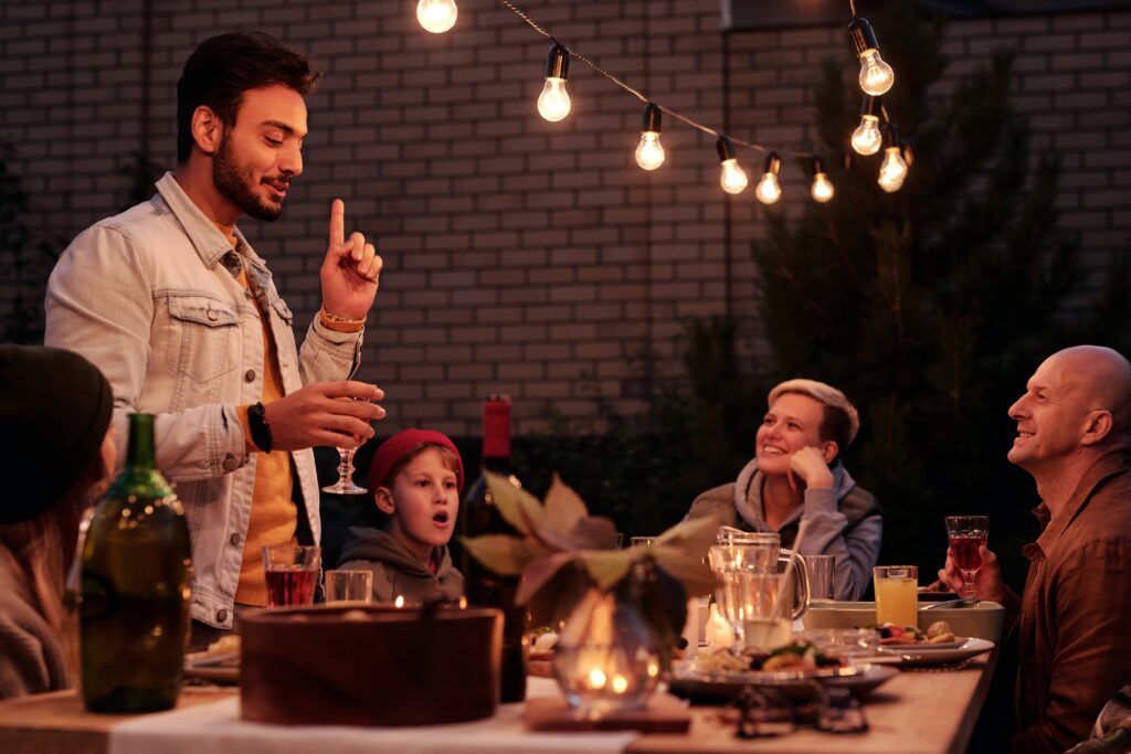Ethnic guy offering toast at dinner with friends