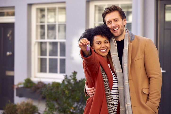 Portrait Of Multi Cultural Couple Outdoors On Moving Day Holding Keys To New Home In Fall Or Winter