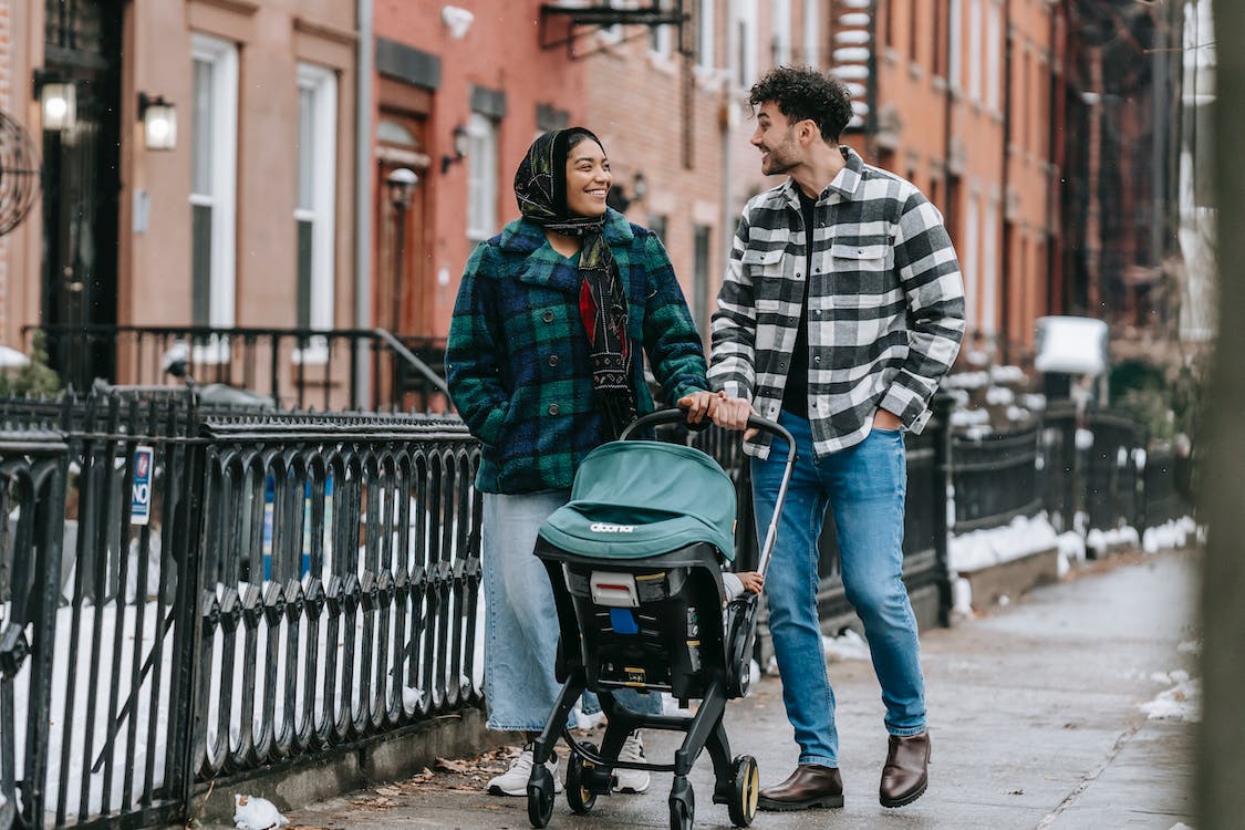 Happy multiethnic parents walking with baby stroller
