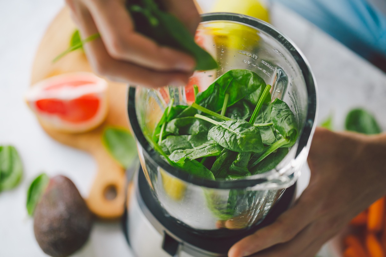 Man cooking healthy detox smoothie with fresh fruits and green spinach