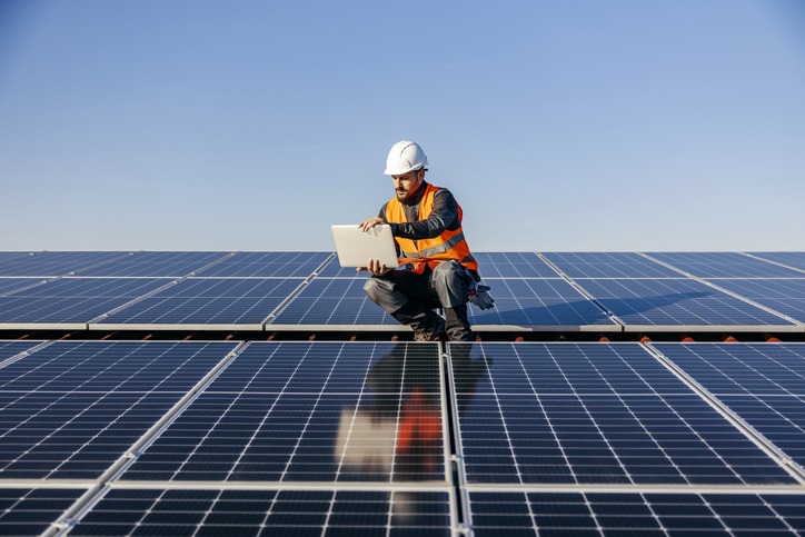 A worker on the roof using laptop charged by sun energy.