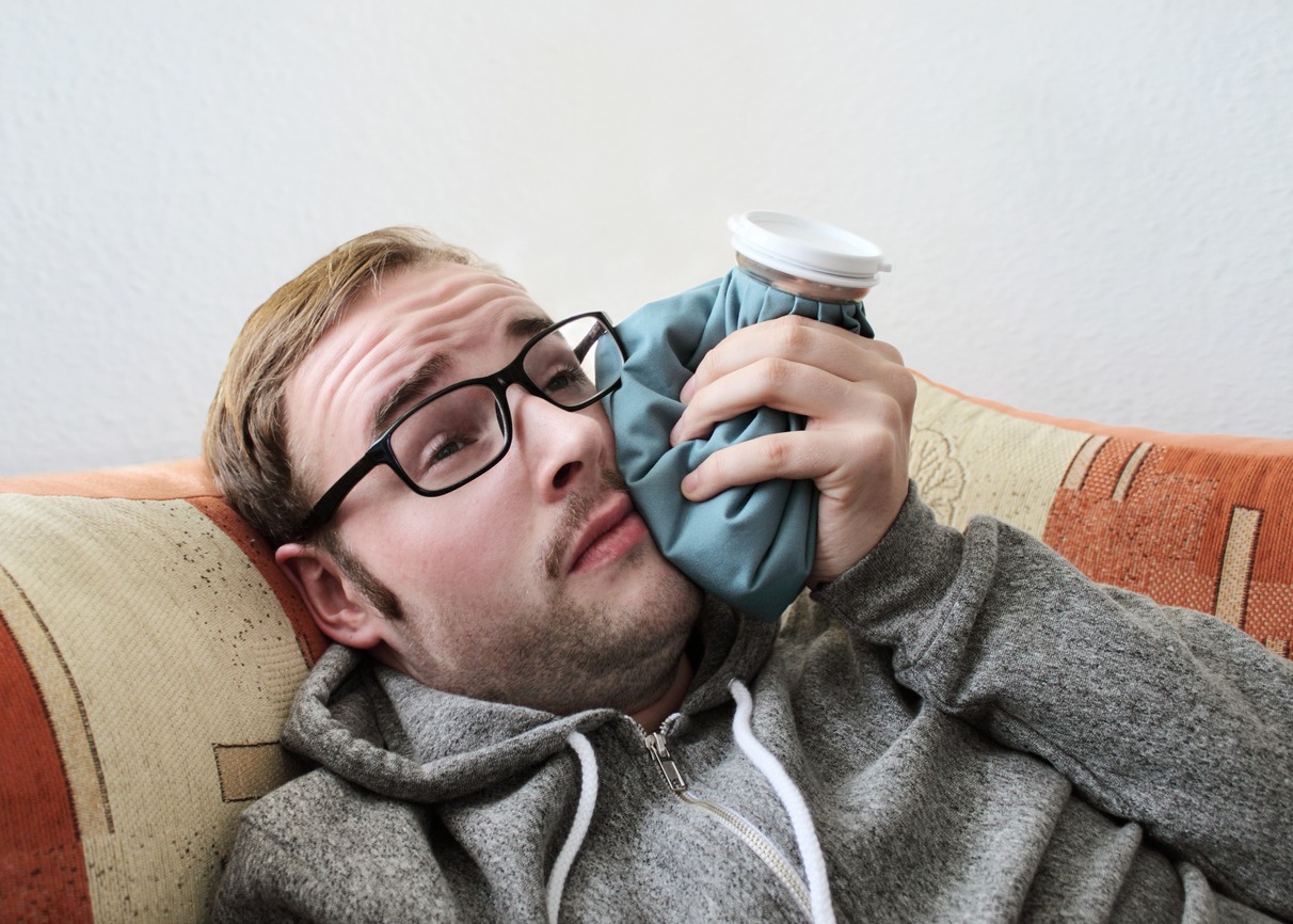 a man with a toothache putting cold compress