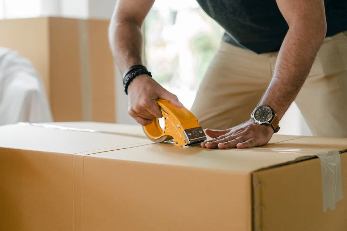 A man securing a box with tape