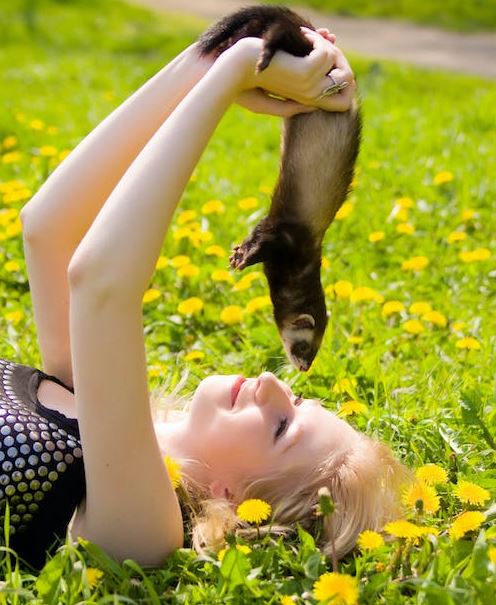 a woman holding a ferret