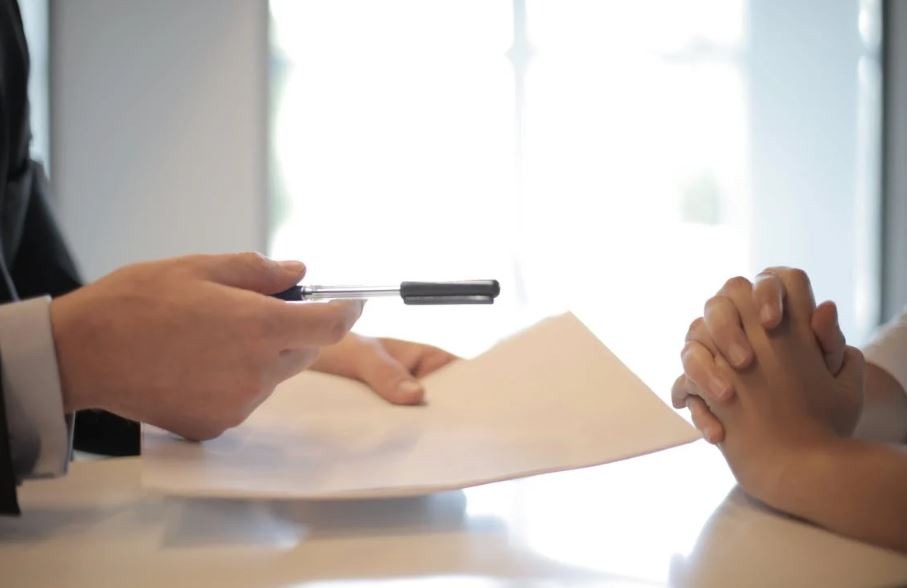 A businessman giving the contract to a woman to sign
