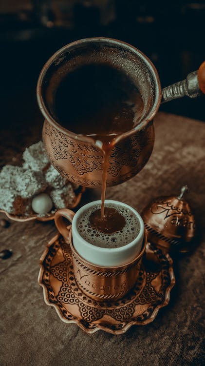 pouring coffee from Turkish ornate copper skillet to cup