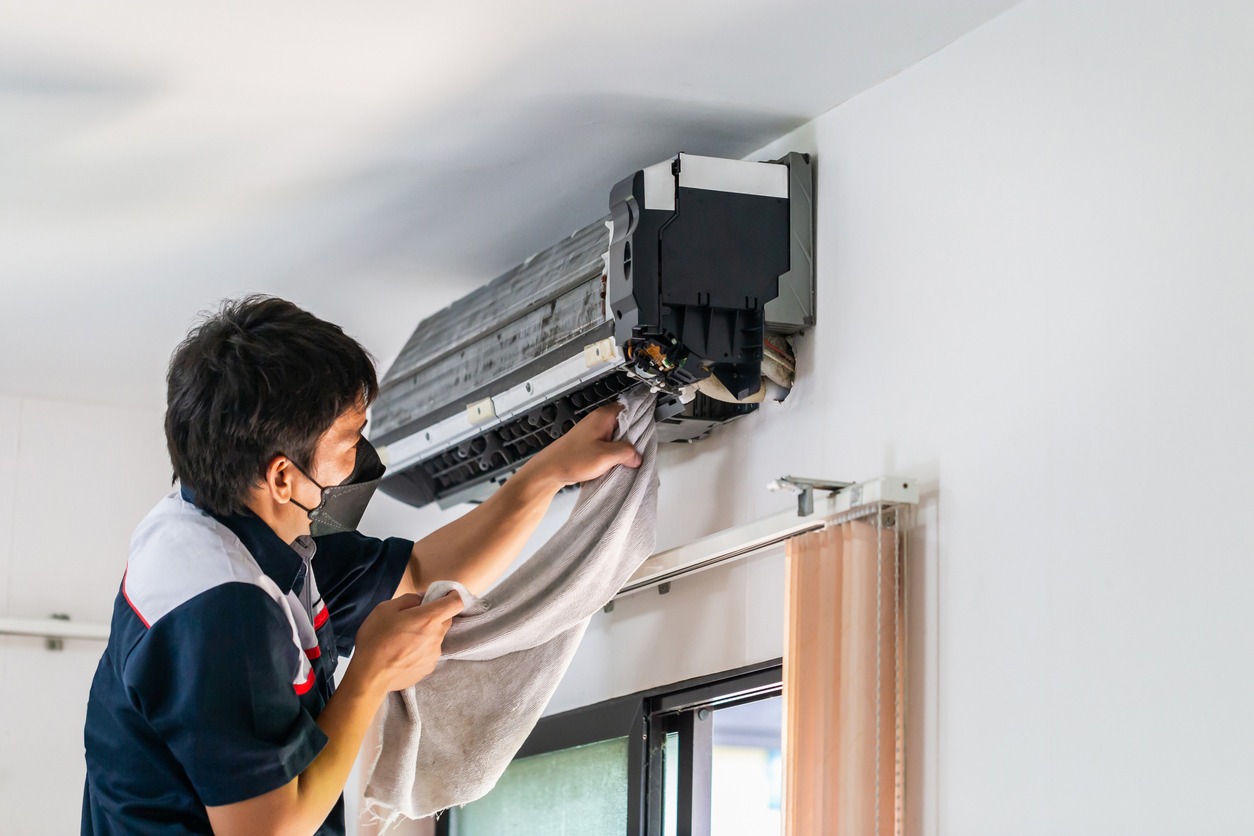 A handyman working on an air condition unit in a room