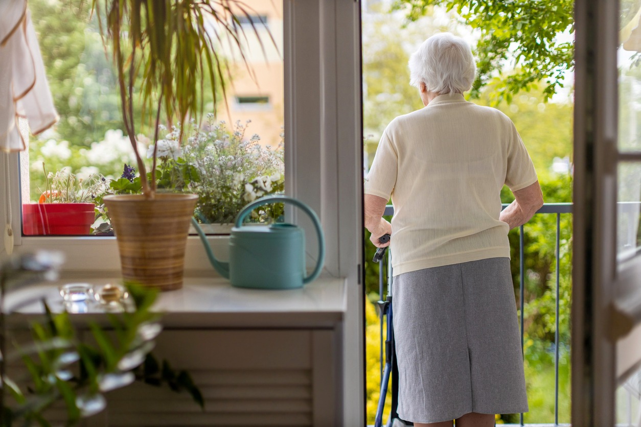a senior woman with a walking frame looking at the backyard