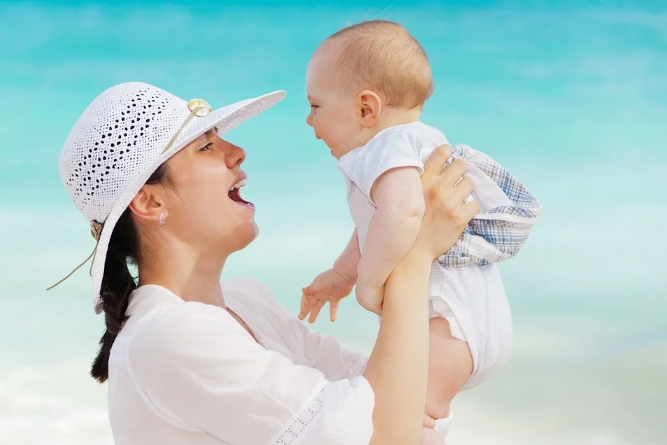 mother-carrying-her-toddler-beach-hat-beach