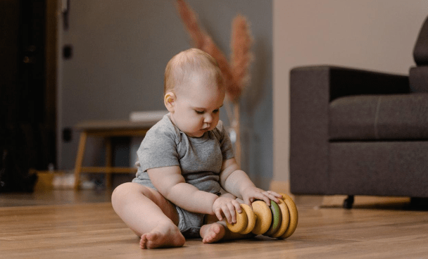 a baby playing with an educational toy while sitting on the floor