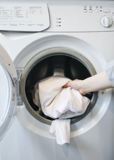 a-person-putting-clothes-in-a-washing-machine