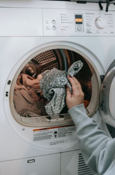 anonymous-woman-putting-clothes-in-washing-machine