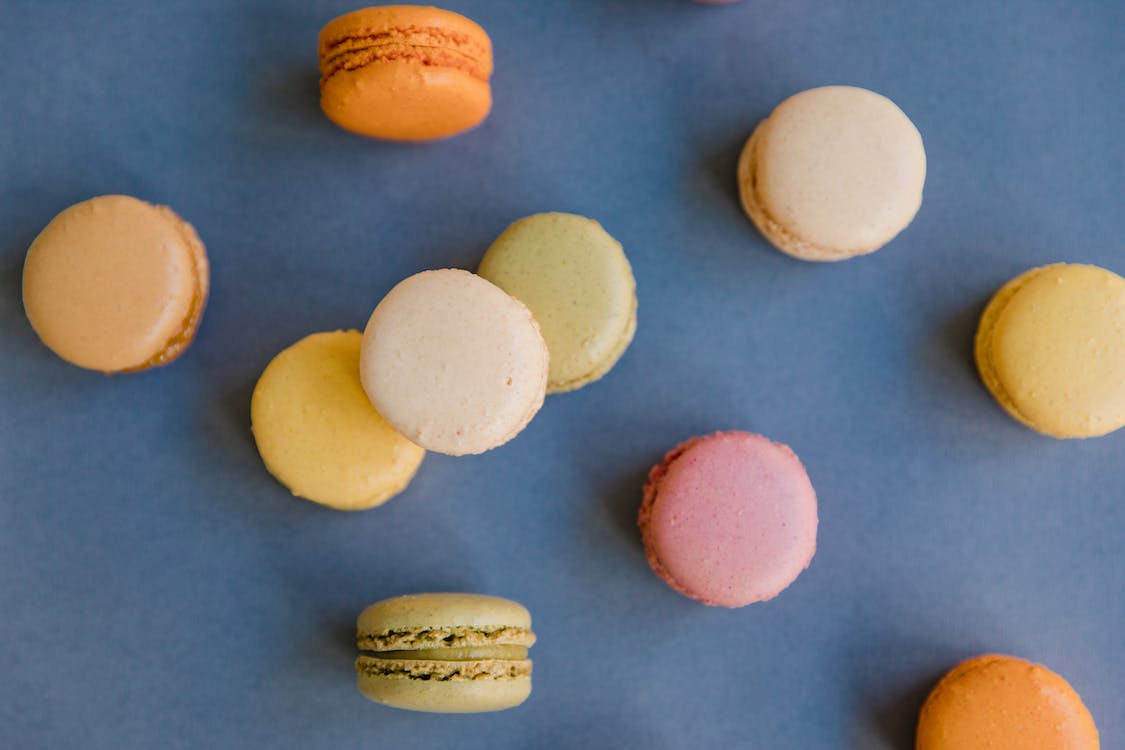 an overhead shot of different flavored macarons on a blue surface